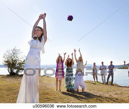 Stock Photograph - Bride throwing bouquet to friends. Fotosearch