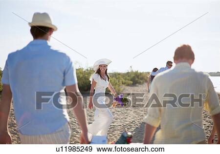 Stock Photo - Bride walking with friends on beach. Fotosearch