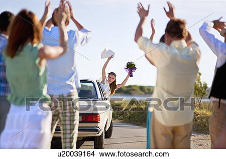Picture - Bride waving to wedding party from car. Fotosearch