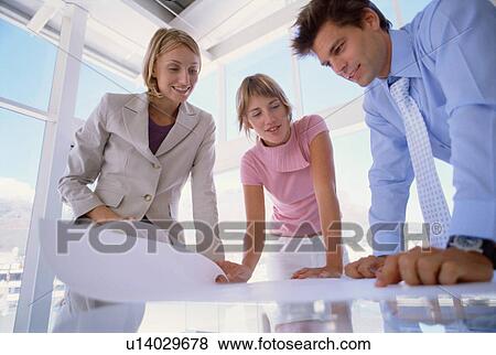 Business people examining plans together View Large Photo Image Stock Photo - Business people examining plans together. Fotosearch