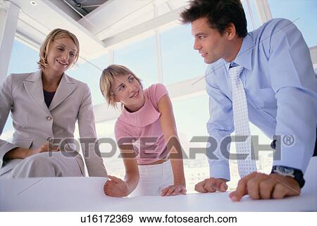 Stock Photo - Business people examining plans together. Fotosearch