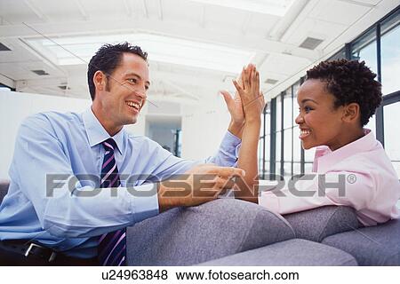 Stock Photo - Business people high fiving on couch. Fotosearch