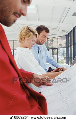Picture - Business people reading together. Fotosearch