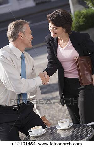 Picture - Business people shaking hands at cafe. Fotosearch