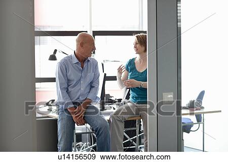 Stock Photo - Business people talking at desk. Fotosearch