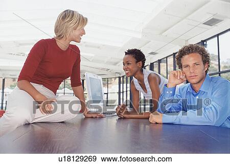 Stock Photo - Business people talking at desk. Fotosearch