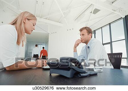 Stock Photograph - Business people talking at desk. Fotosearch
