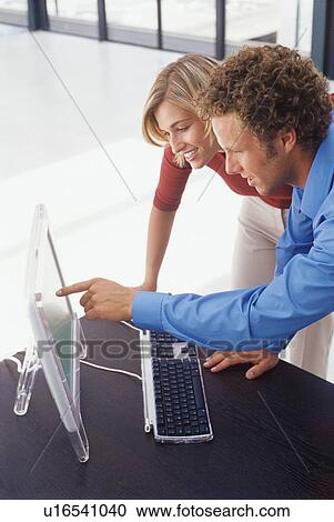 Stock Image - Business people using computer together. Fotosearch