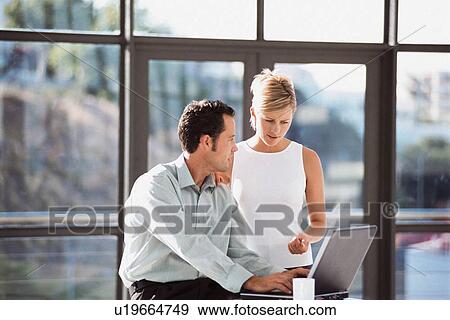 Stock Photo - Business people using laptop in office. Fotosearch