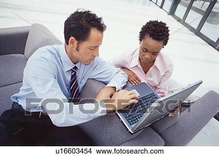 Picture - Business people using laptop together. Fotosearch