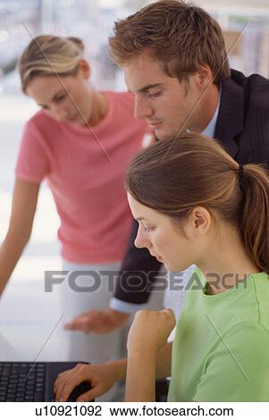 Stock Image - Business people using laptop together. Fotosearch