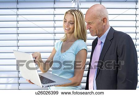 Stock Photo - Business people using laptop together. Fotosearch