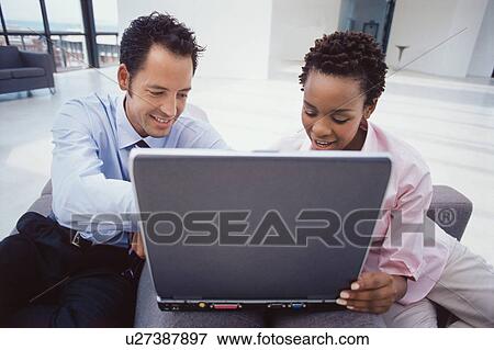 Stock Photo - Business people using laptop together. Fotosearch