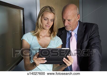 Stock Image - Business people using tablet together. Fotosearch