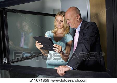 Business people using tablet together View Large Photo Image Stock Photo - Business people using tablet together. Fotosearch