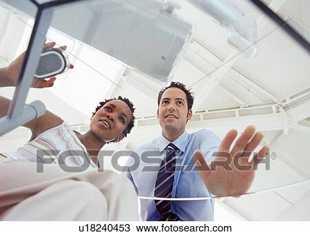 Stock Image - Business people working at desk together. Fotosearch