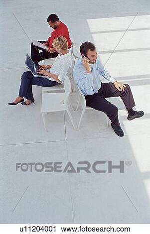 Stock Image - Business people working in lobby. Fotosearch