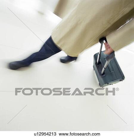 Stock Image - Business person rolling luggage. Fotosearch