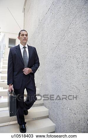 Stock Image - Businessman carrying briefcase on steps. Fotosearch