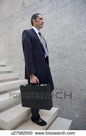 Stock Image - Businessman carrying briefcase on steps. Fotosearch