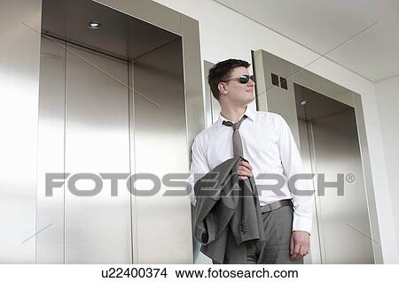 Businessman carrying jacket in lobby View Large Photo Image Picture - Businessman carrying jacket in lobby. Fotosearch