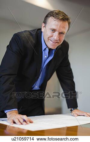 Businessman examining blueprints View Large Photo Image Picture - Businessman examining blueprints. Fotosearch