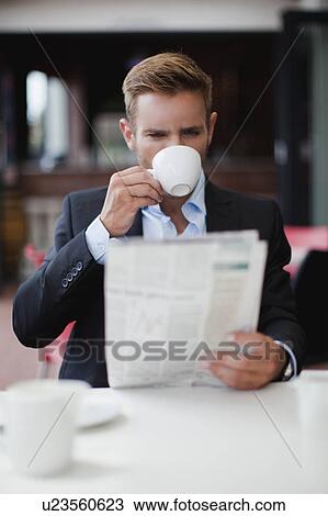 Stock Image - Businessman having coffee with newspaper. Fotosearch