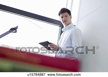 Businessman holding book in office View Large Photo Image Stock Photo - Businessman holding book in office. Fotosearch