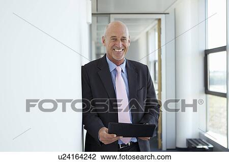 Stock Image - Businessman holding tablet in office. Fotosearch