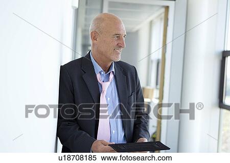 Businessman holding tablet in office View Large Photo Image Stock Photography - Businessman holding tablet in office. Fotosearch