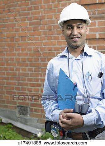 Businessman in hard hat carrying folder View Large Photo Image Stock Photo - Businessman in hard hat carrying folder. Fotosearch
