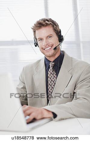 Stock Photo - Businessman in headset using laptop. Fotosearch