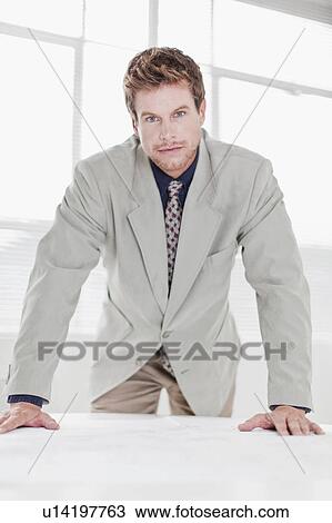 Businessman leaning over desk in office View Large Photo Image Stock Image - Businessman leaning over desk in office. Fotosearch