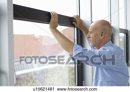 Businessman looking out office window View Large Photo Image Stock Image - Businessman looking out office window. Fotosearch