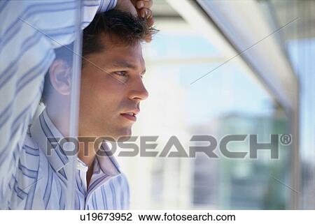 Stock Image - Businessman looking out office window. Fotosearch