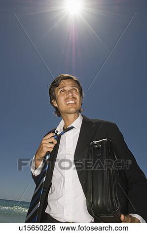 Stock Photo - Businessman loosening his tie on beach. Fotosearch
