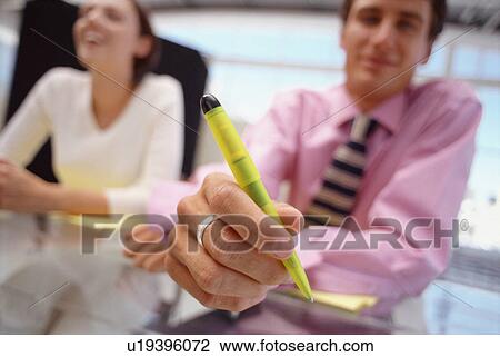 Stock Image - Businessman offering pen in meeting. Fotosearch