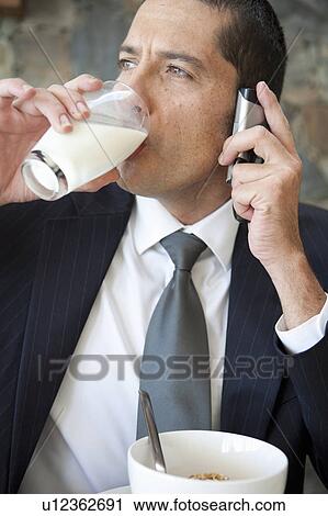 Stock Image - Businessman on cell phone at breakfast. Fotosearch