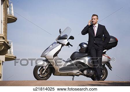 Businessman on cell phone with scooter View Large Photo Image Stock Photography - Businessman on cell phone with scooter. Fotosearch