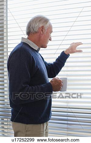 Stock Photo - Businessman peering out office window. Fotosearch