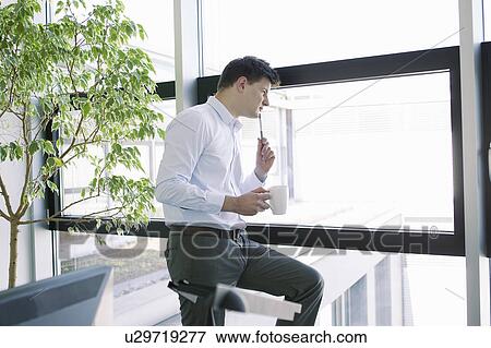 Stock Photo - Businessman peering out office window. Fotosearch