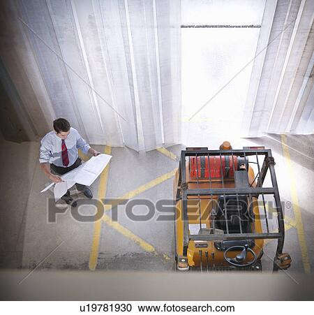 Businessman reading blueprints on site View Large Photo Image Stock Image - Businessman reading blueprints on site. Fotosearch