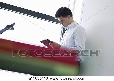 Businessman reading book in office View Large Photo Image Stock Image - Businessman reading book in office. Fotosearch