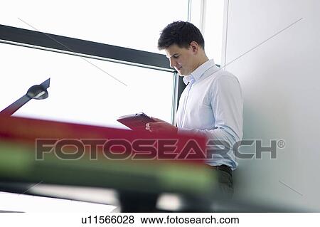 Businessman reading book in office View Large Photo Image Stock Photo - Businessman reading book in office. Fotosearch