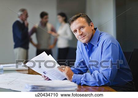 Stock Image - Businessman reading in meeting. Fotosearch