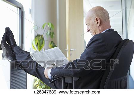 Businessman reading with feet up View Large Photo Image Stock Photo - Businessman reading with feet up. Fotosearch
