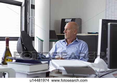 Businessman relaxing with feet on desk View Large Photo Image Picture - Businessman relaxing with feet on desk. Fotosearch