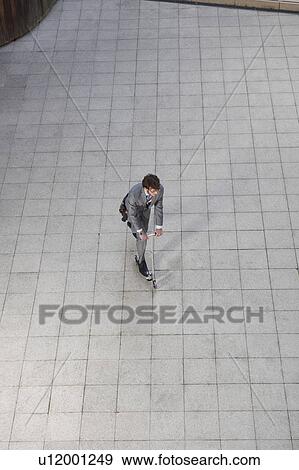 Businessman riding scooter in courtyard View Large Photo Image Stock Photo - Businessman riding scooter in courtyard. Fotosearch
