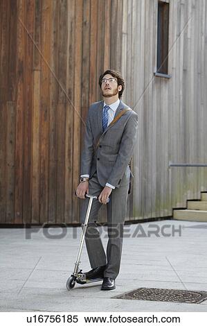 Stock Photography - Businessman riding scooter in courtyard. Fotosearch