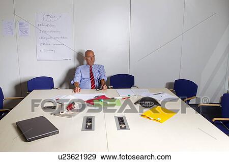 Stock Photo - Businessman sitting at conference desk. Fotosearch